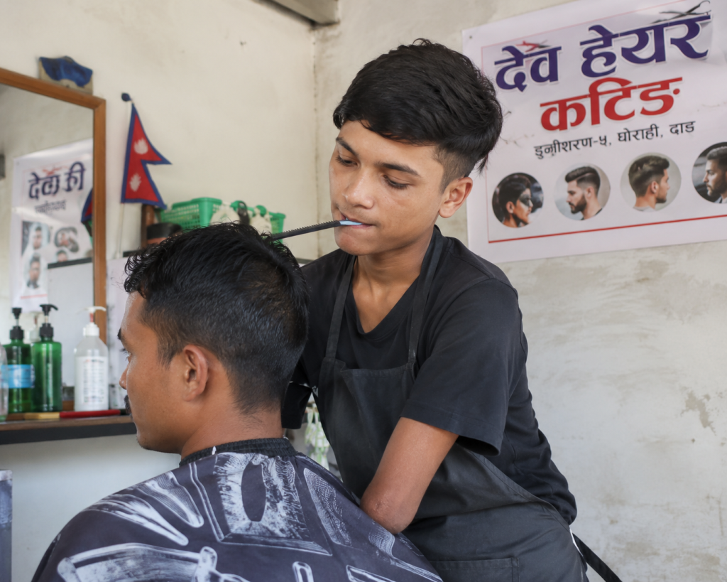 दाङका १८ वर्षीय देवबहादुर परियार आफ्नै सैलुनमा कपाल काट्दै