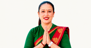 हरियो ब्लाउज र रातो सारीमा नमस्कार गर्दै मुस्कुराएकी रीता थापामगर।